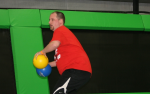 Man Holding Two Dodgeballs in Trampoline Arena